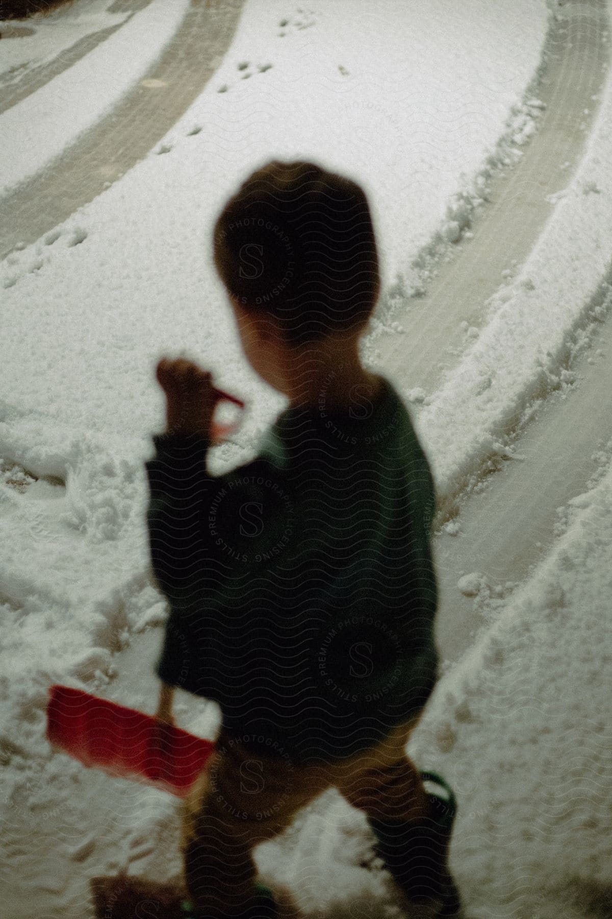 A child with a shovel in his hands removing snow from the ground.