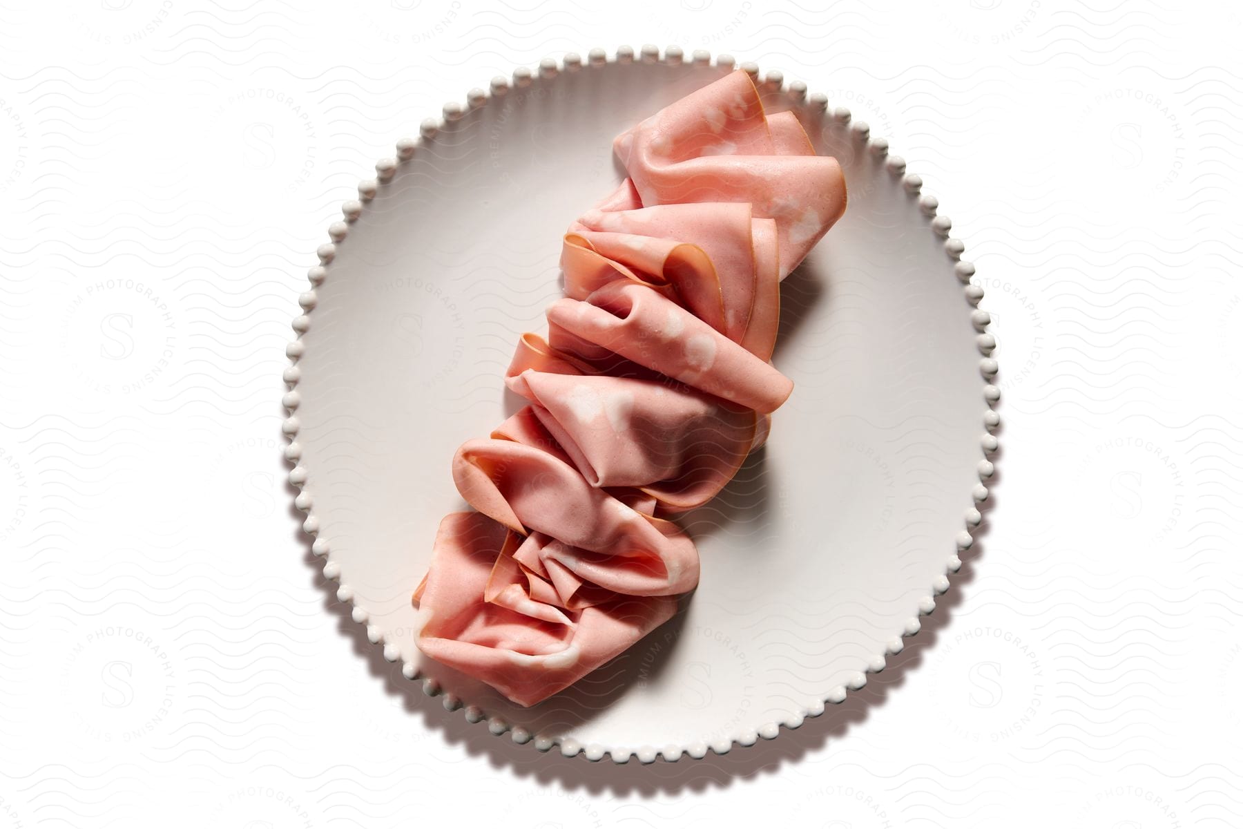 Thin sliced ham is arranged across a plate