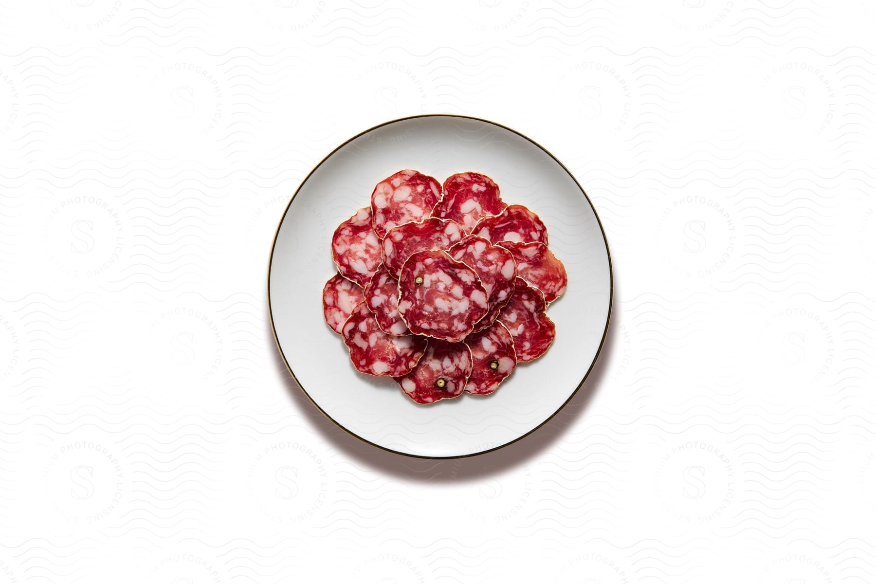 White plate with sliced salami arranged in a spiral.