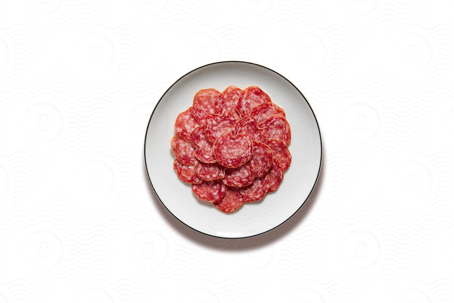 Spanish salami on a white plate placed on a white surface