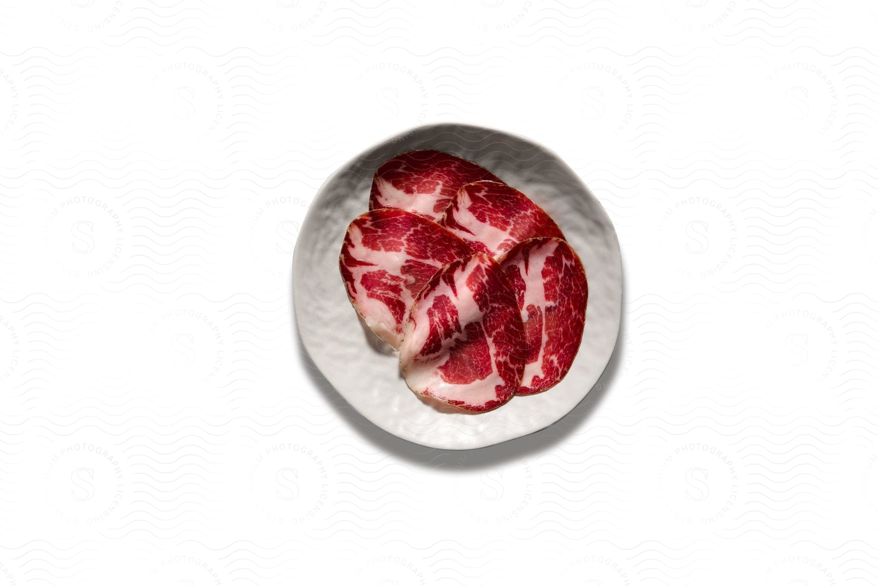 Raw steak is lying on a white plate
