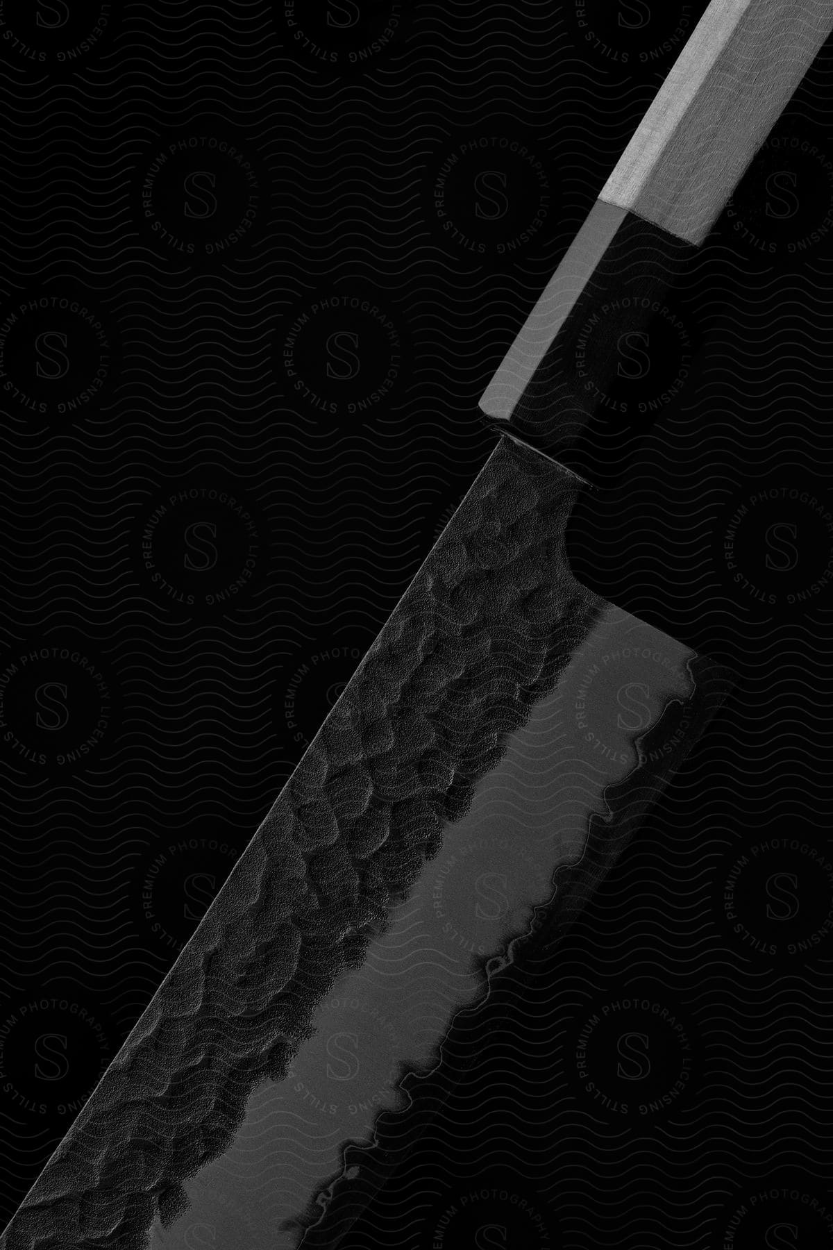 A large butcher knife sitting in a dark room.