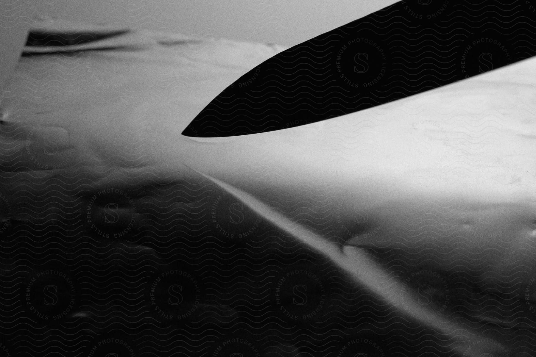 Silhouette of a knife blade over wrinkled paper