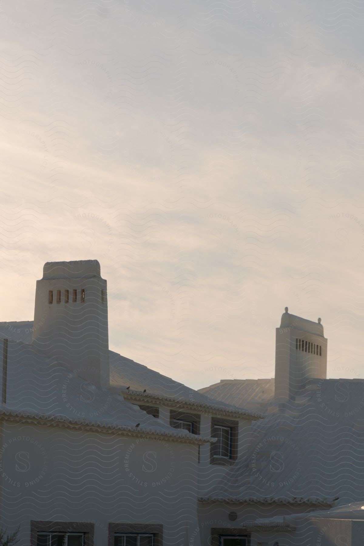 A white building with a tall tower against a sunset sky.