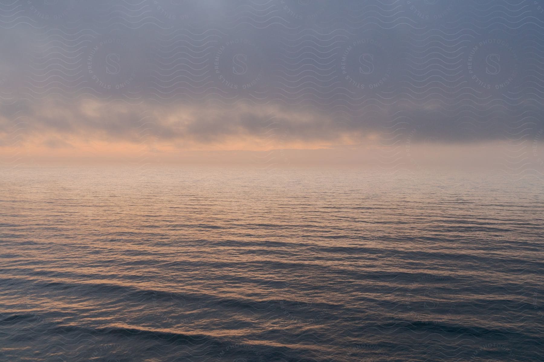 Ripples in a calm sea under cloud cover.