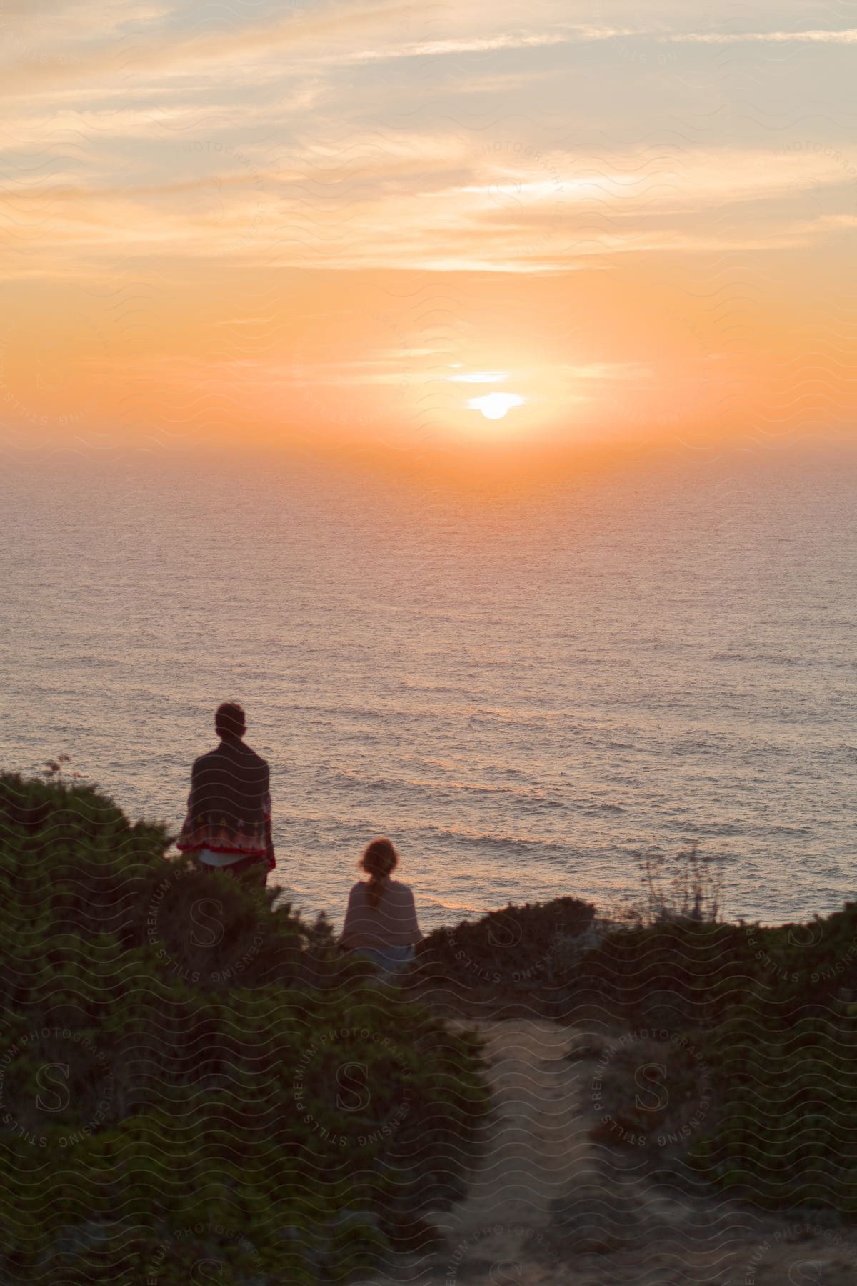 Two people sitting outdoors watching the sunrise.