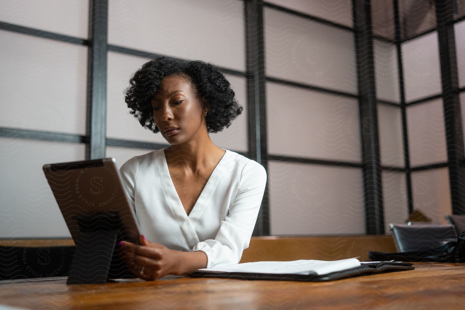 Woman sitting at desk in office uses tablet.