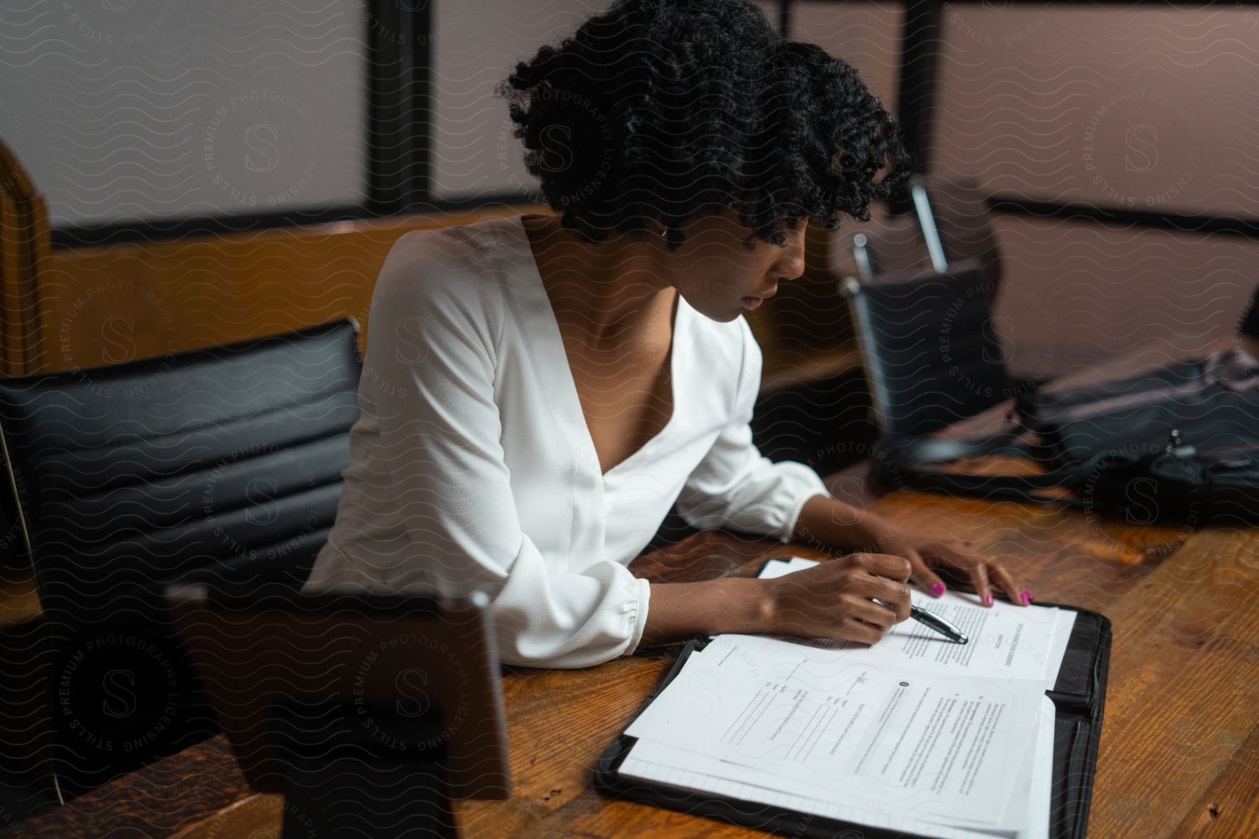 Woman sitting at a desk, reading a document.