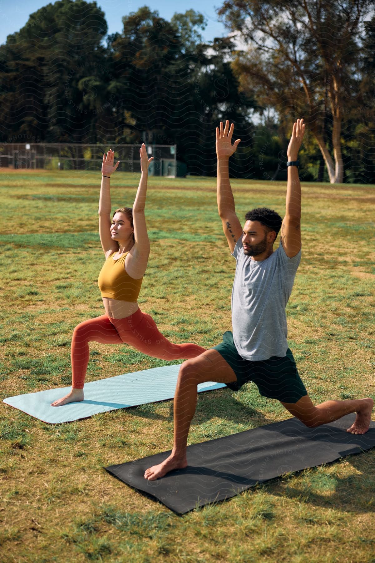man and a woman doing yoga on a grass field during the day