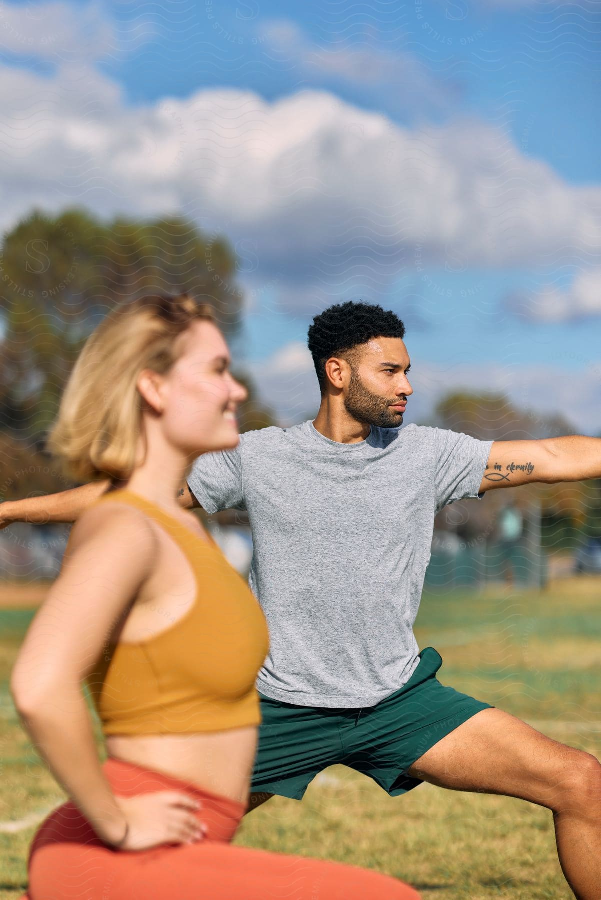 A man and woman stretching on an athletic field.