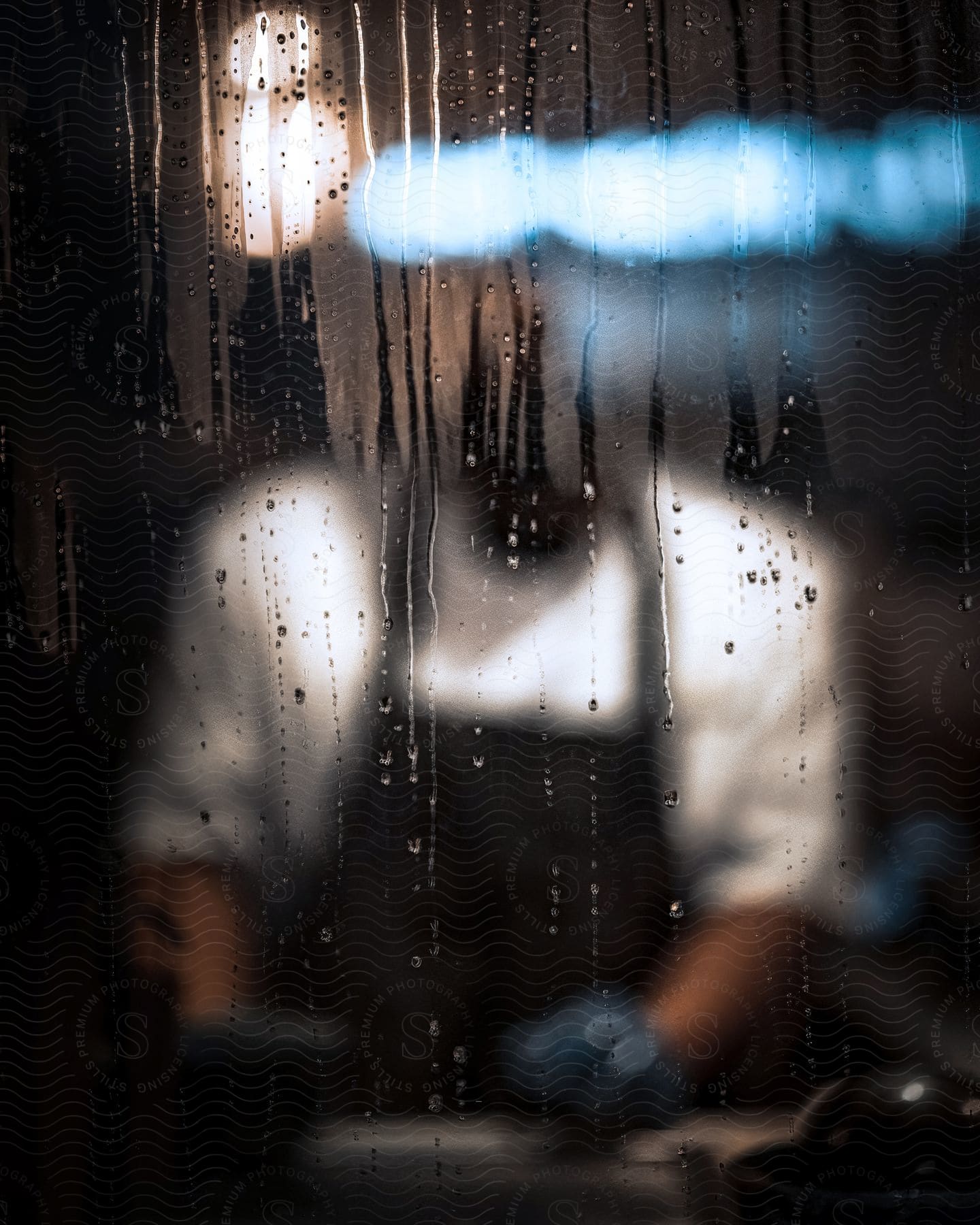 Fogged window with water droplets, and in the background, a man wearing an apron and gloves.