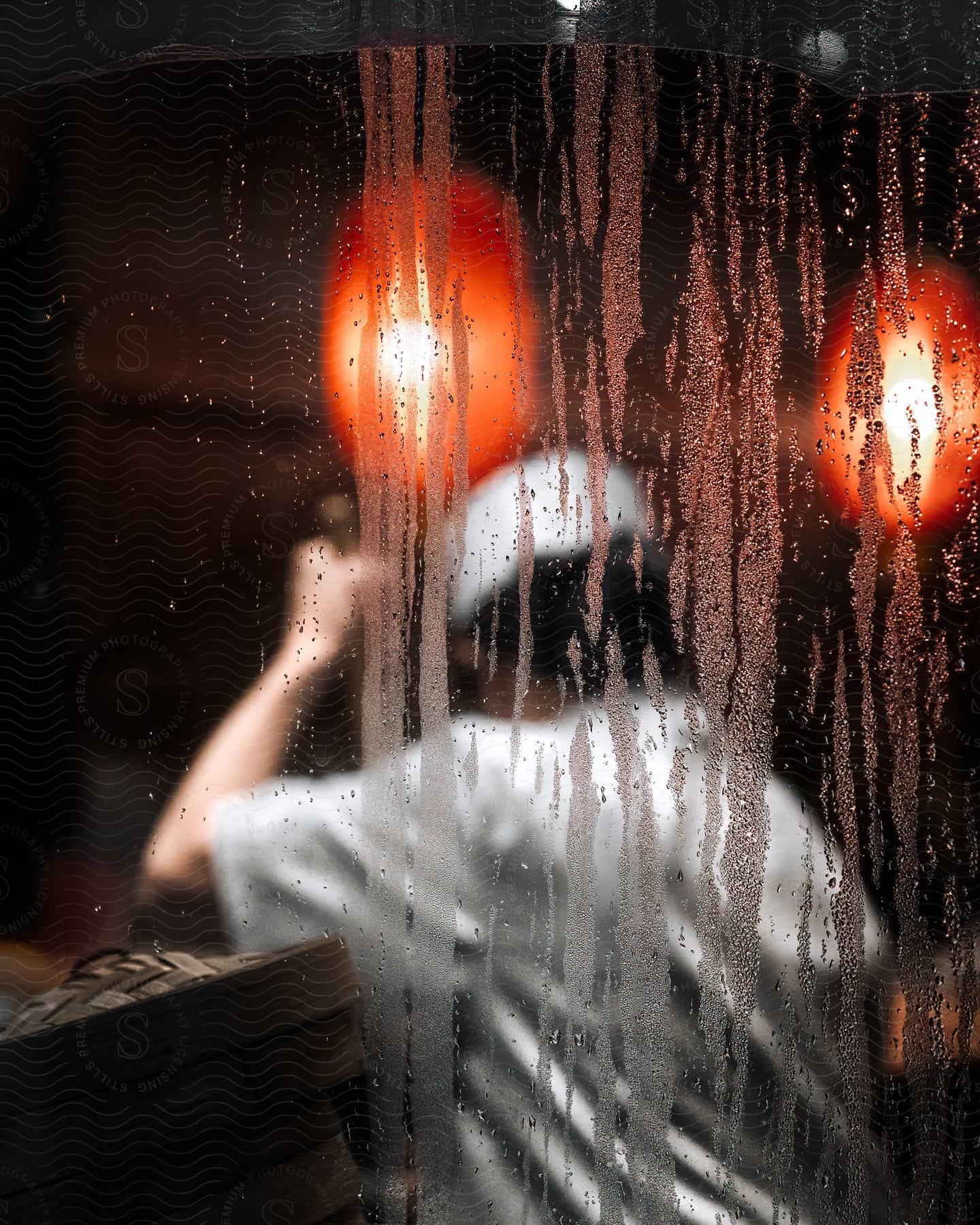 An adult in a white uniform holds a broom as seen through an outside window.