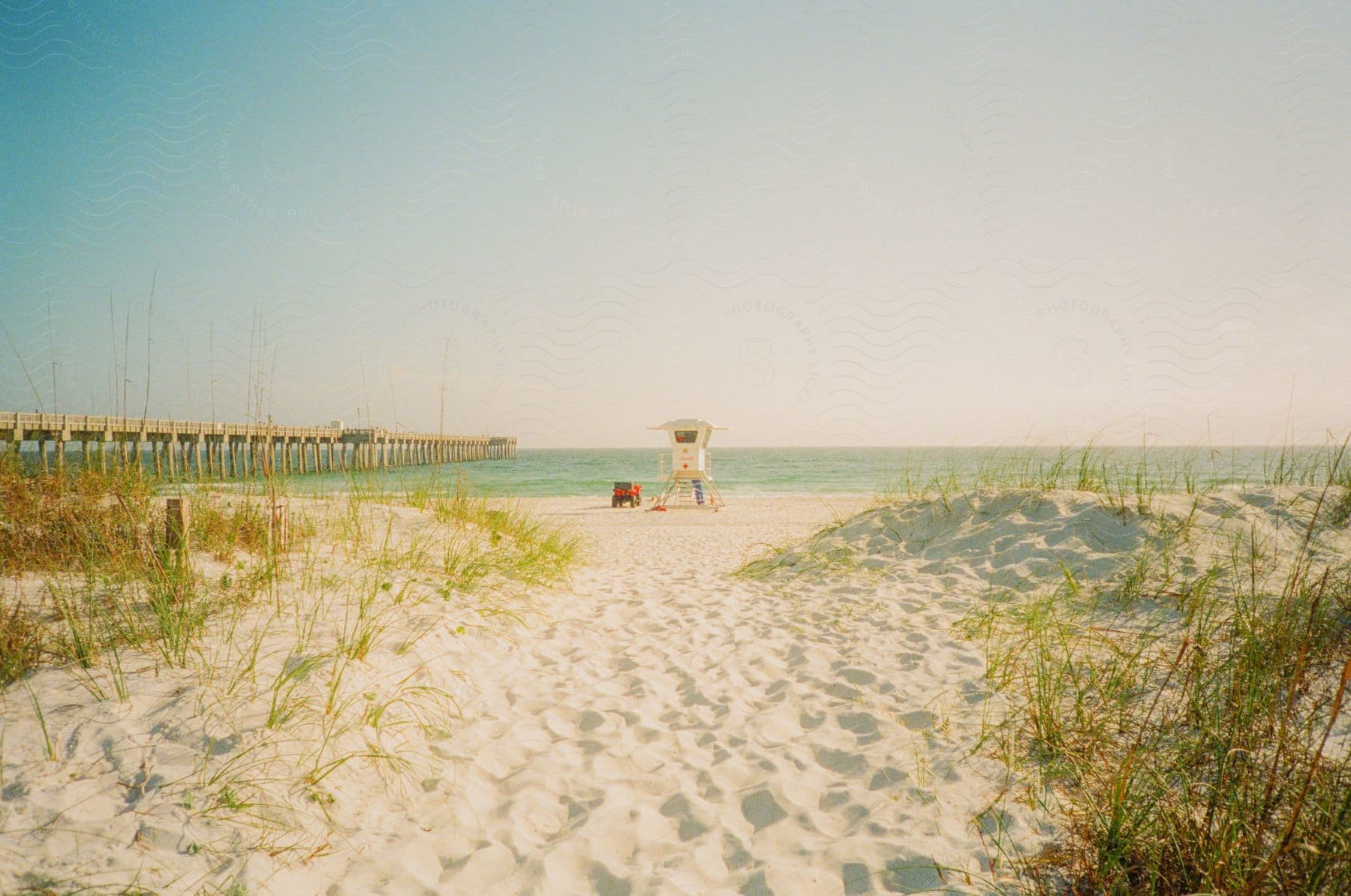 A lifeguard tower stands on the beach near the pier