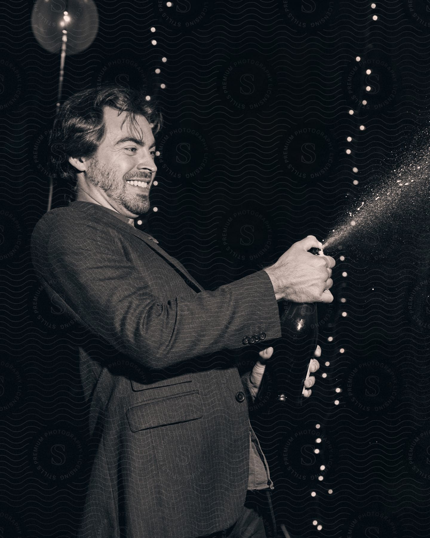 A man shaking up a bottle of champagne and spraying it around.