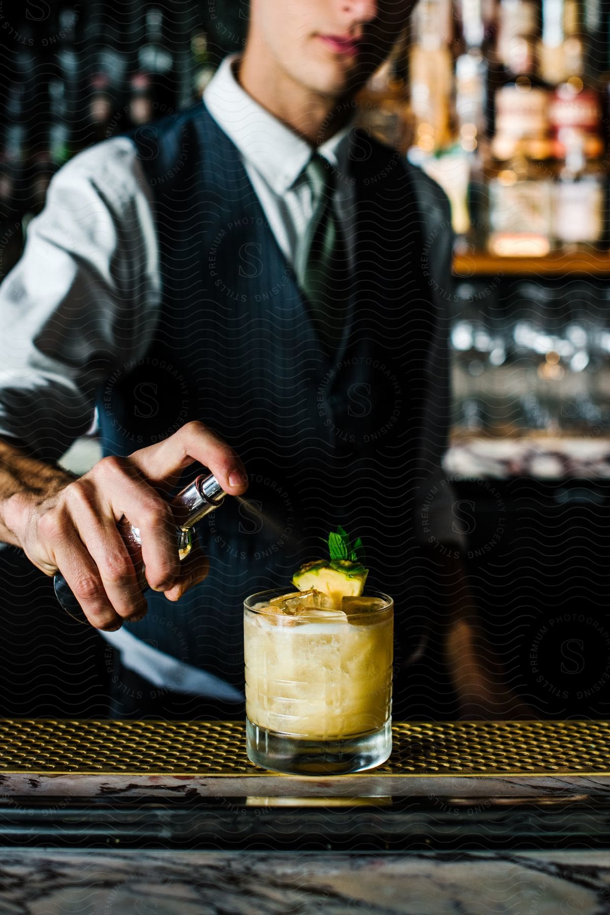 The bartender sprays onto the cocktail.