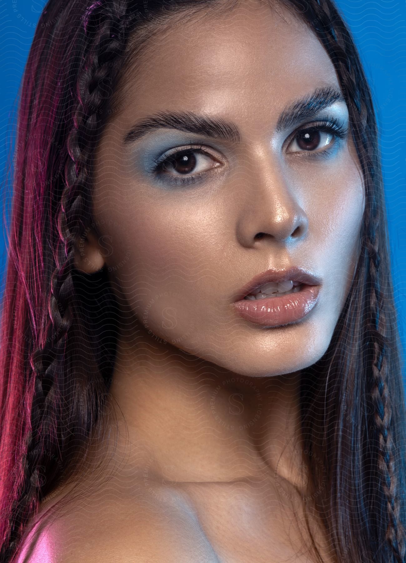 Portrait of a young woman with braided hair and blue eyeshadow.