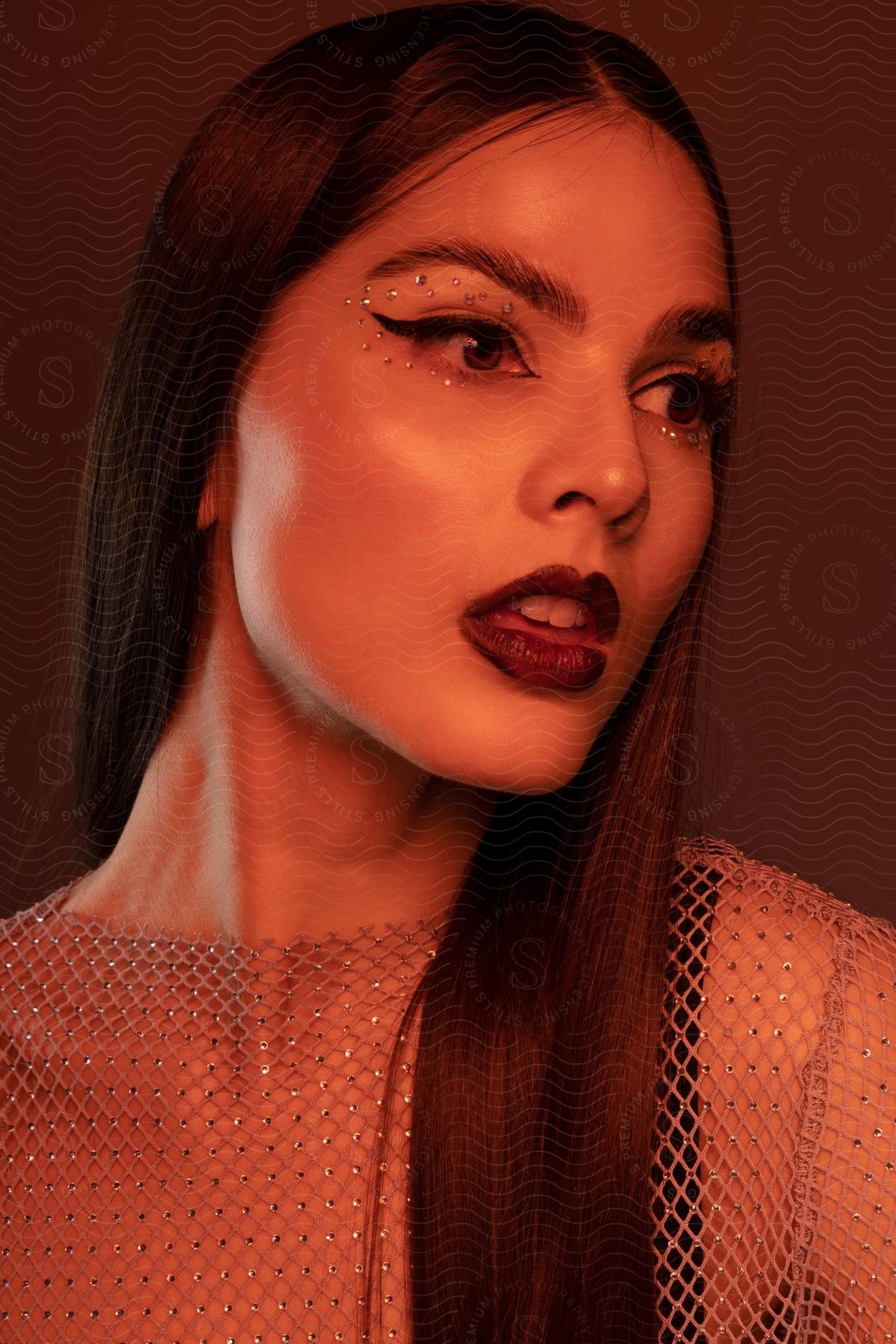 A woman in heavy makeup and sheer net top with mouth open.