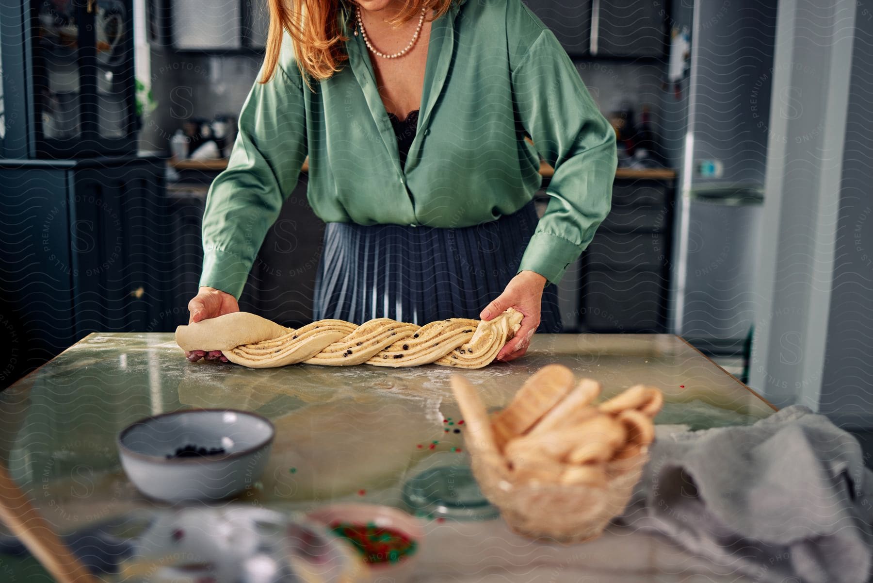 Woman on a kitchen counter with hands in cookie dough.