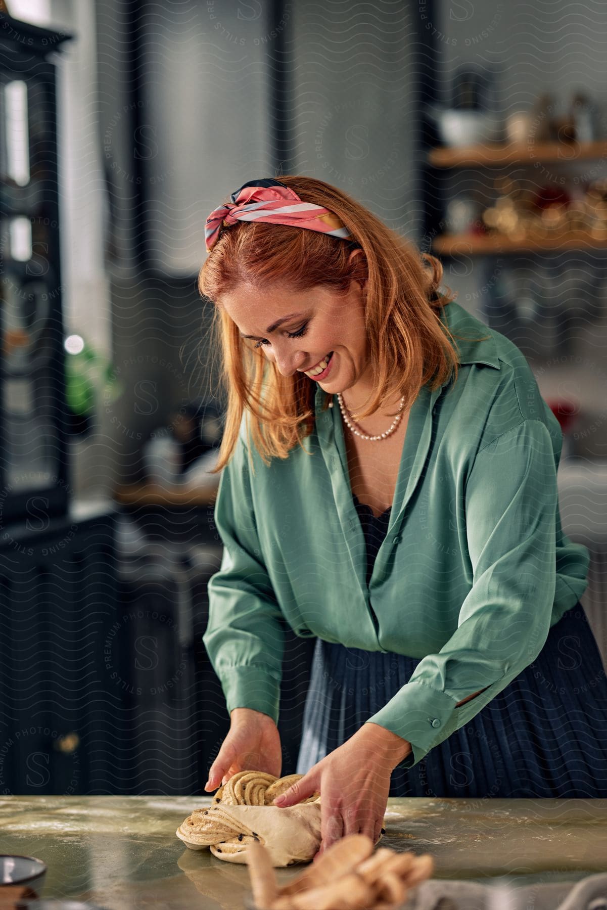 A woman folding dough on the dining table.