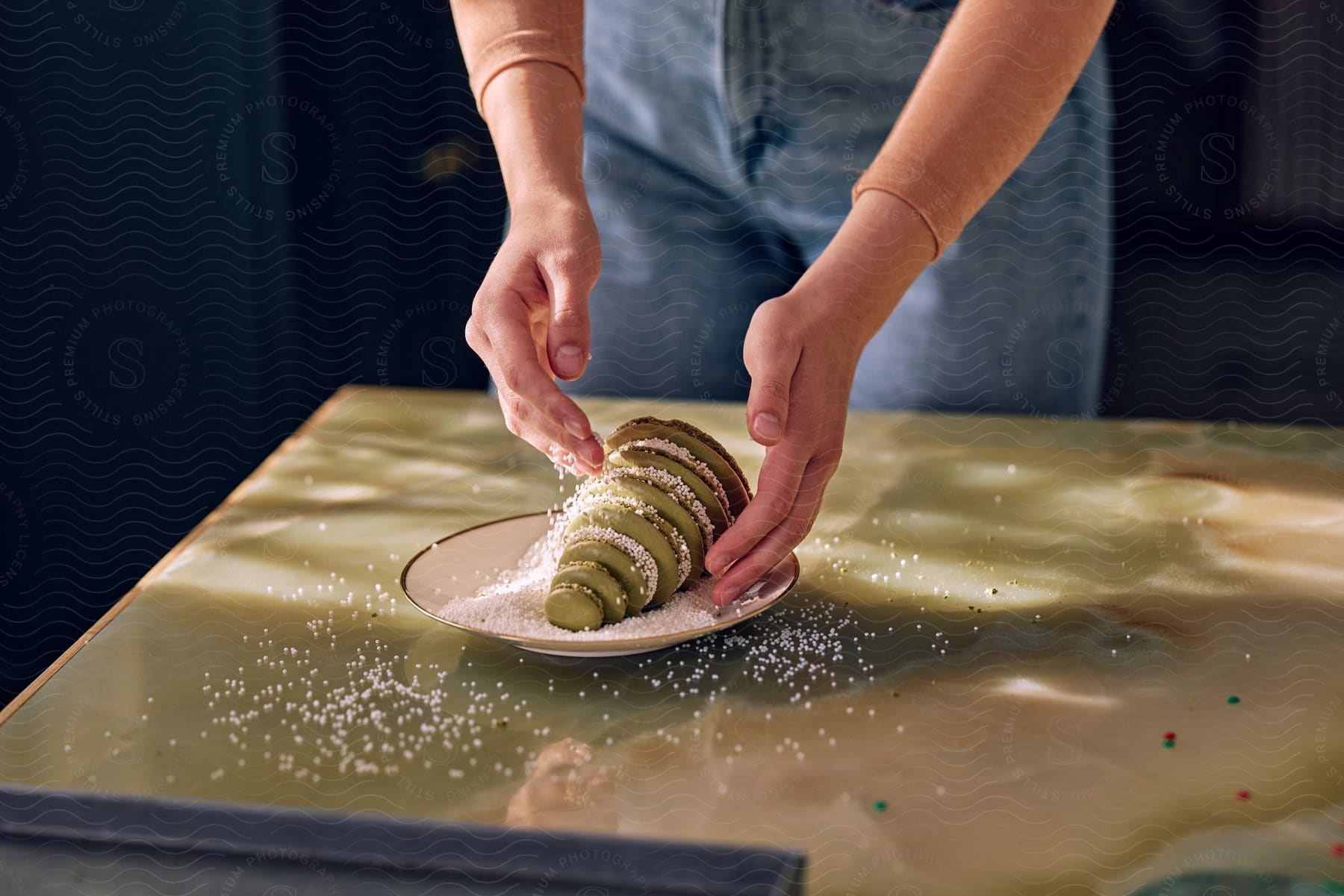 A woman sprinkling coconut flakes on a macaroon Christmas tree