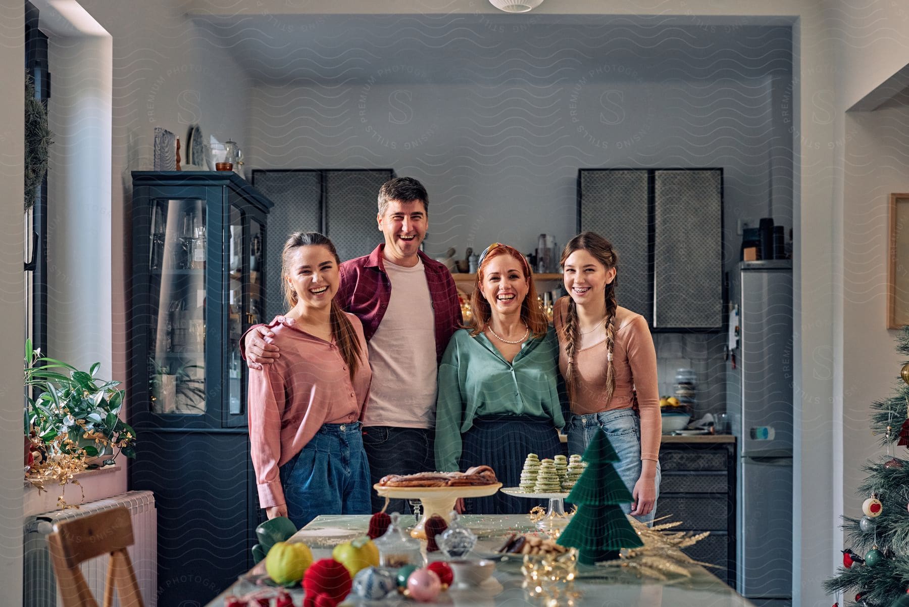 A family posing in a kitchen in front of a plate of Christmas cookies and a pastry wreath.