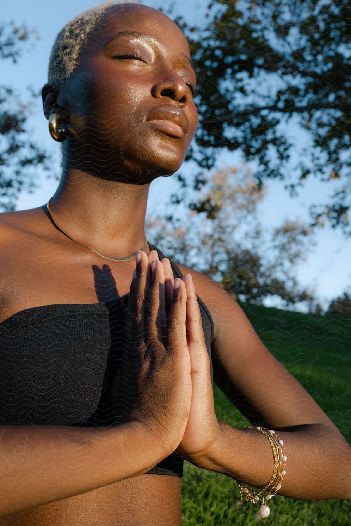 An African woman practices yoga in a park on a sunny day.