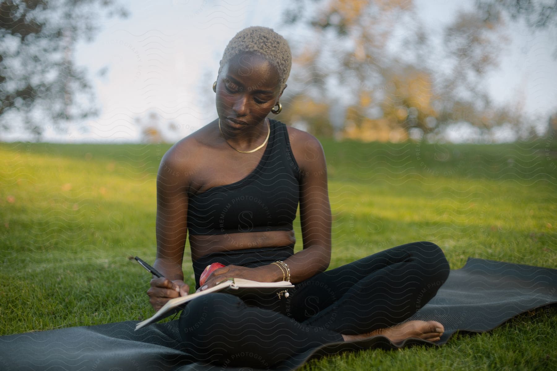 A woman sitting in a park taking notes in a notebook.