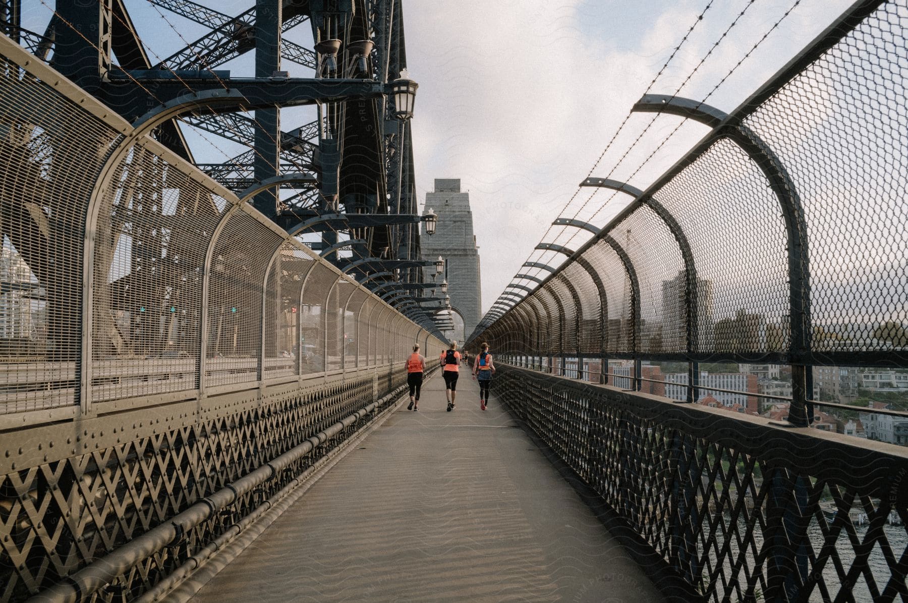 Women walking on a bridge in a metropolis with their backs turned.