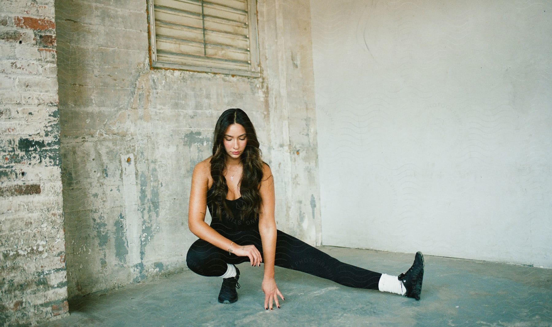 A woman is balancing on one foot with the other leg stretched out and her fingers on the floor