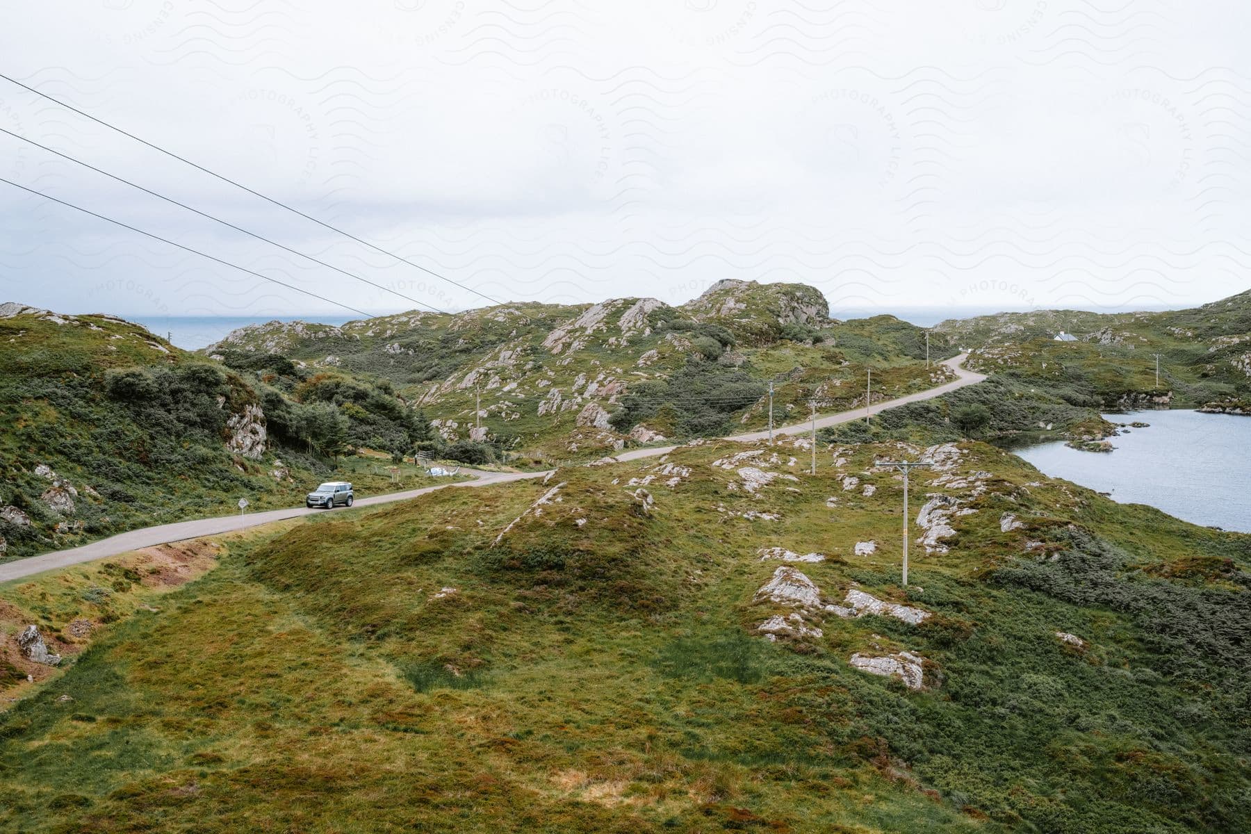 An automobile travels on a road through the mountains along the coast