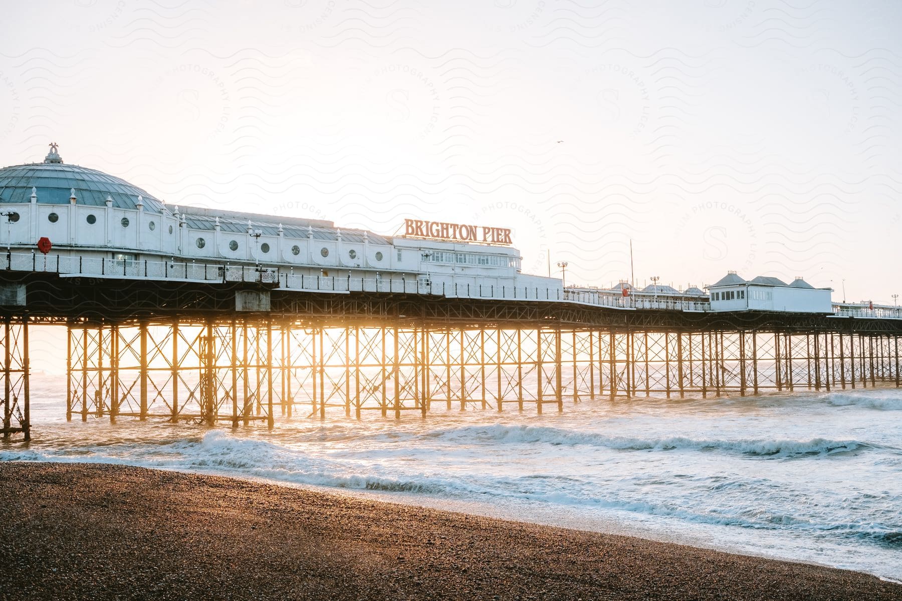 View of Brighton Pier above the sea under a morning sky.