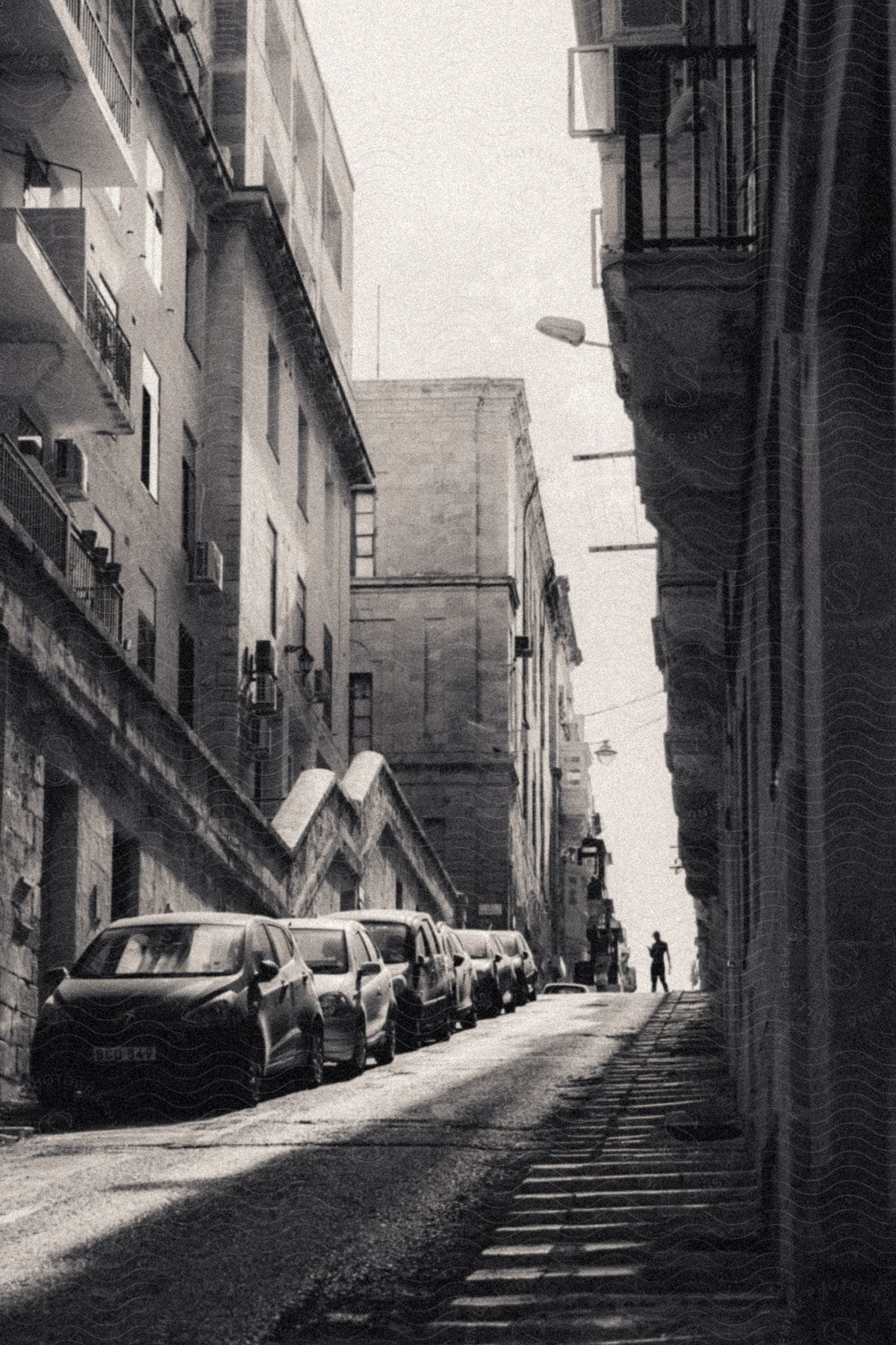 A person standing at the top of a hill in a city with buildings.