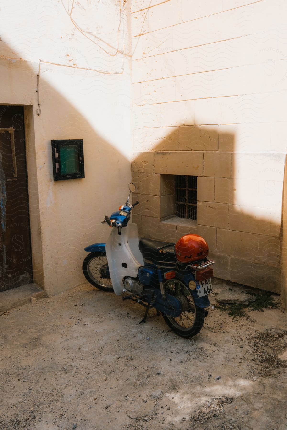 A Vespa scooter stands near a wall and door of a building