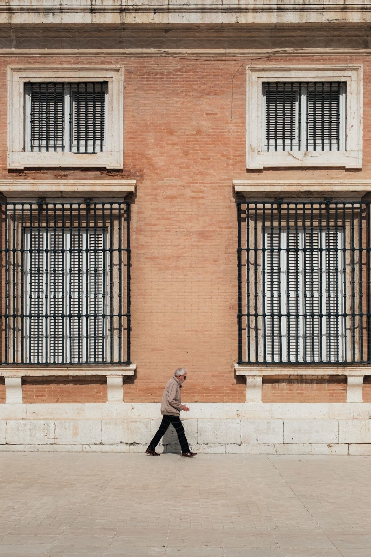 A man walking down a sidewalk next to a building.
