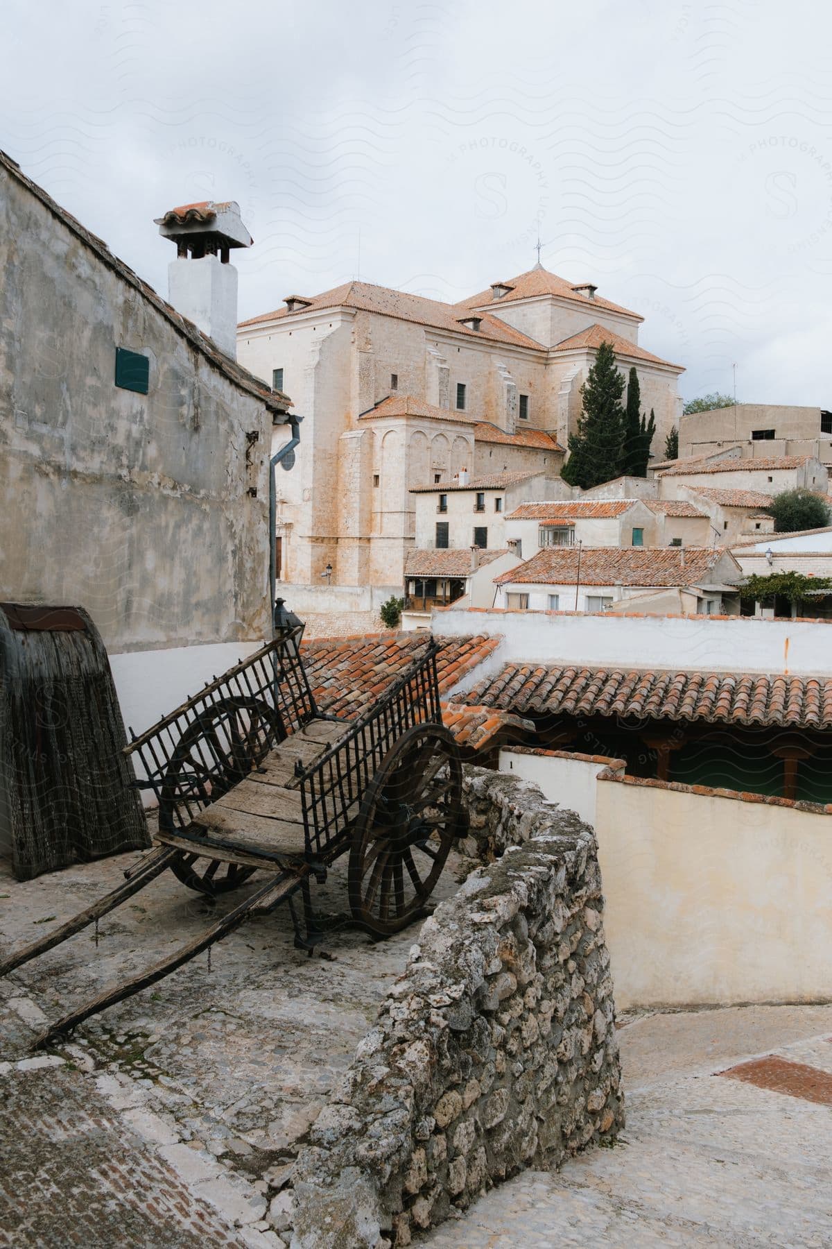 a small town with ancient structures and a wooden wheelbarrow packed beside a building