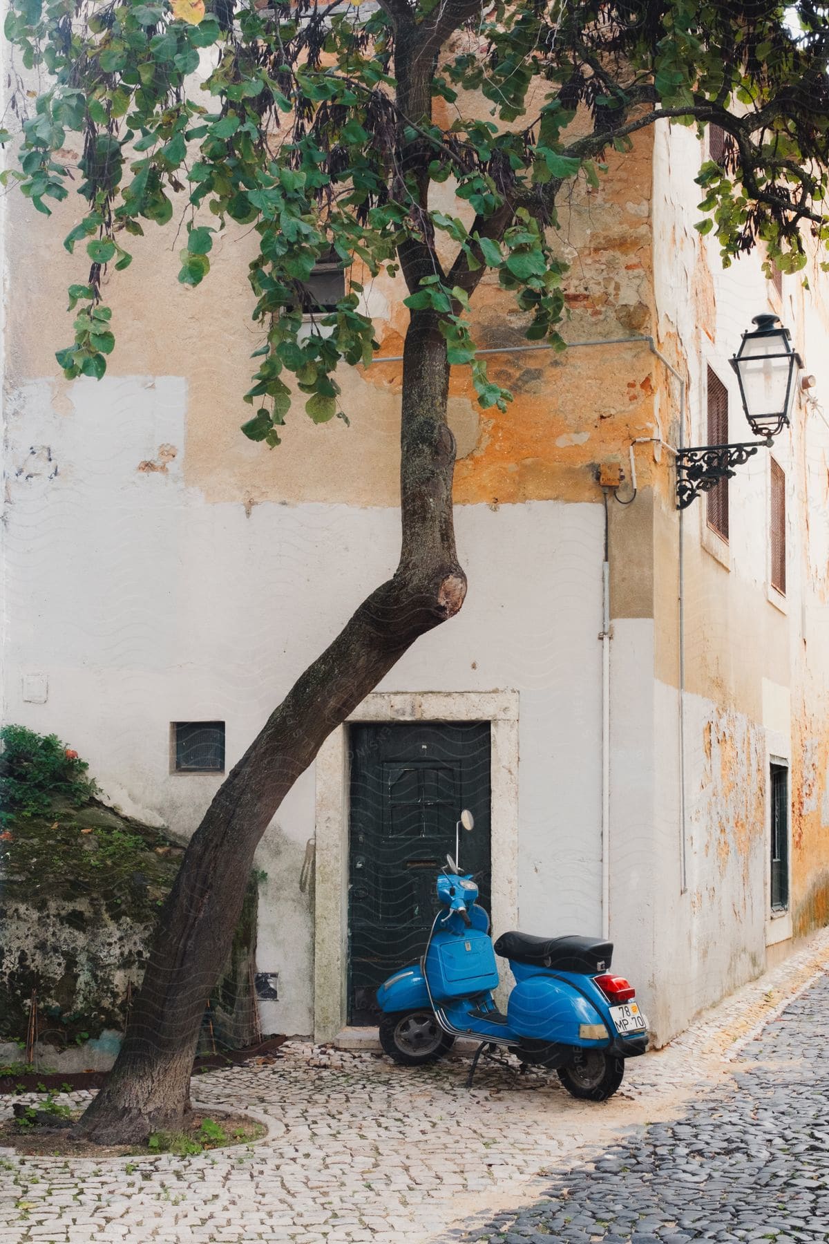 A blue moped neatly parked near a building on the street.
