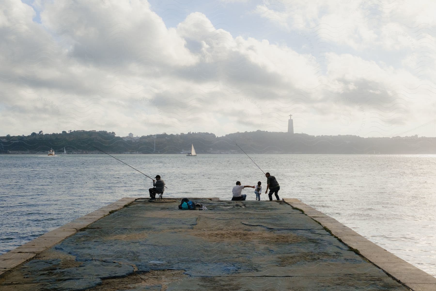 A group of people fishing off of a pier into the ocean