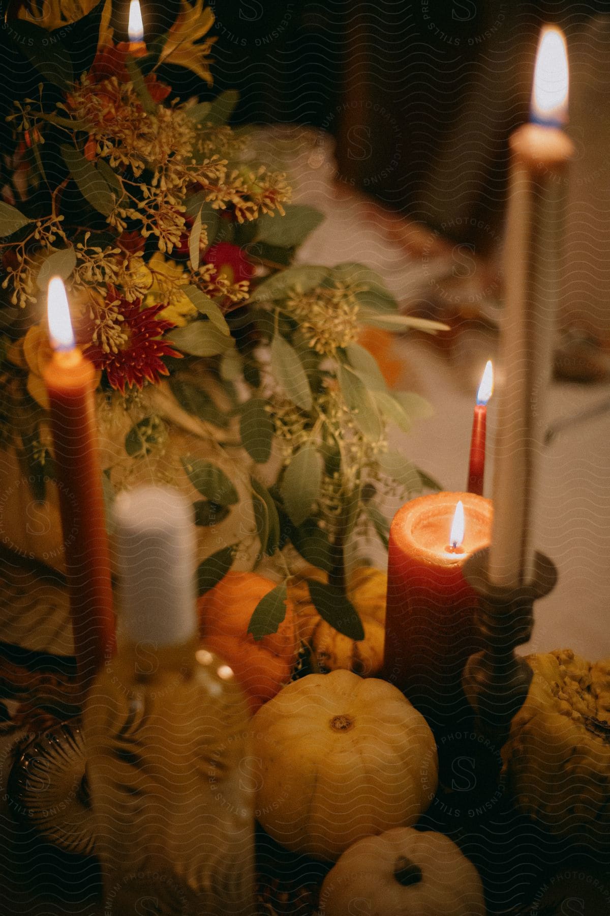 Candles, flowers and mini pumpkins arranged as a centerpiece.