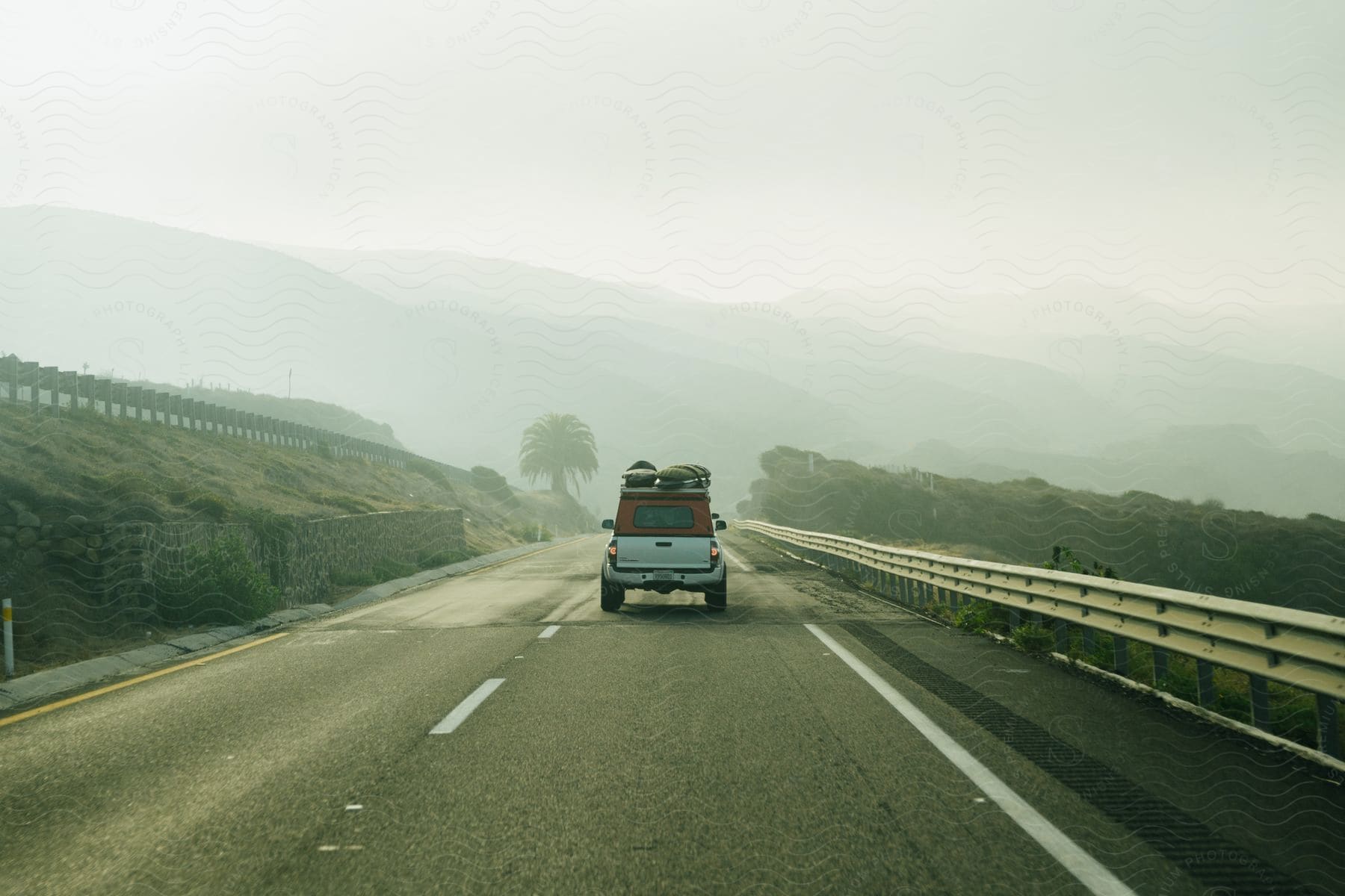 A Pickup Truck Driving Down A Highway With Luggage On Top