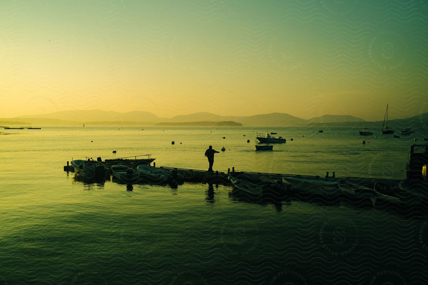 A man walking on a pier next to some boats in the water.