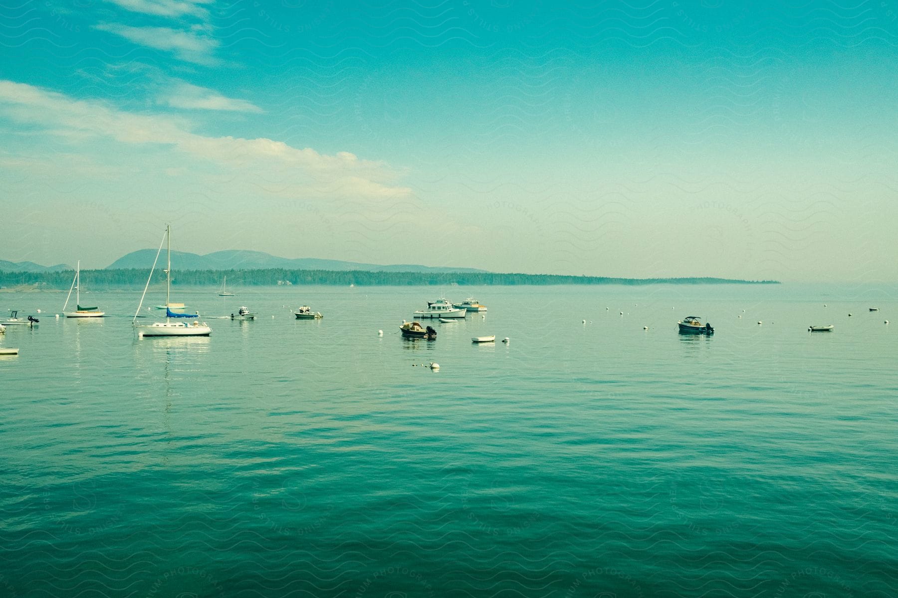 A group of boats all sitting out on the water on a sunny day.