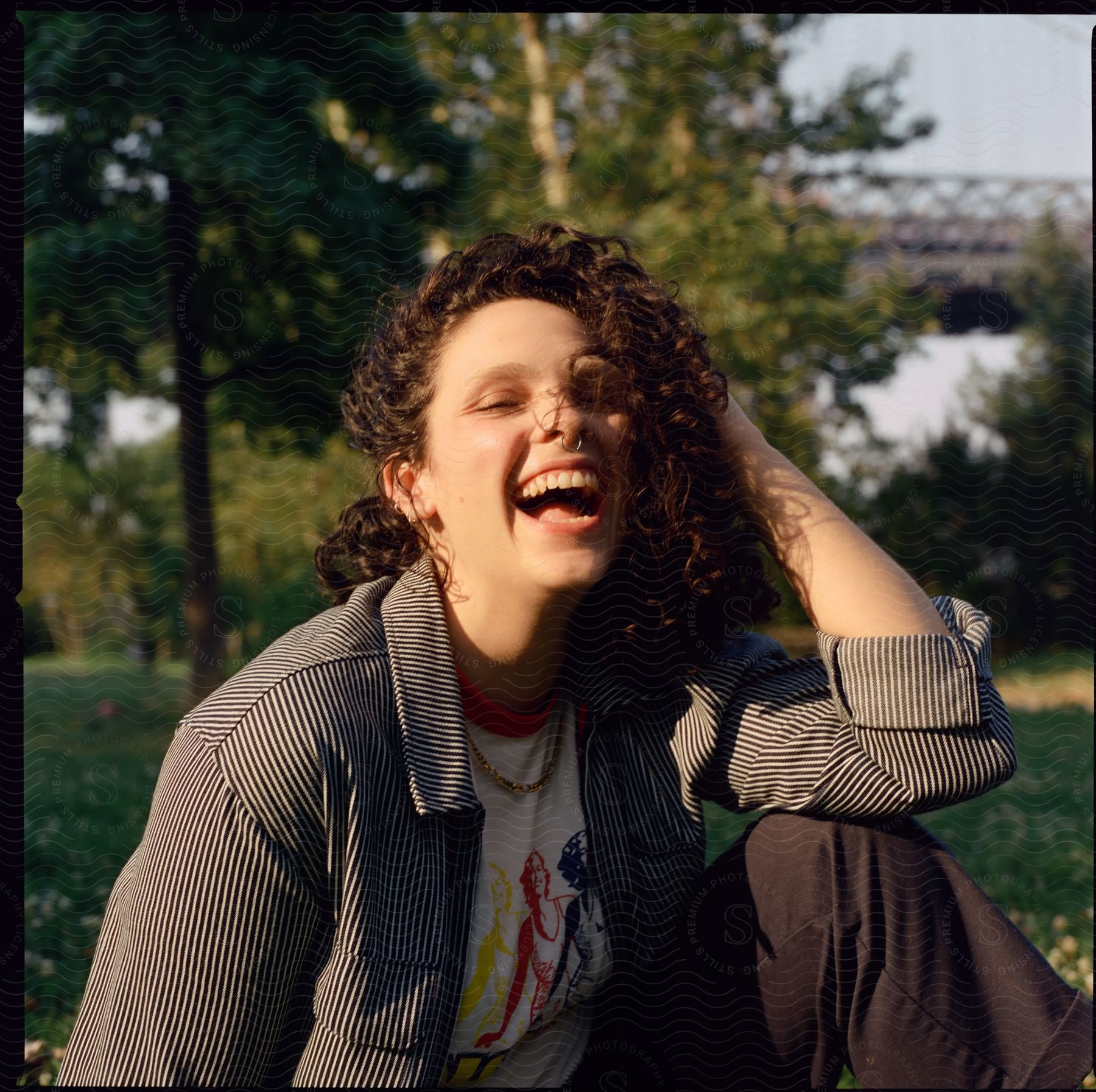 A smiling young woman in a park during sunny weather.