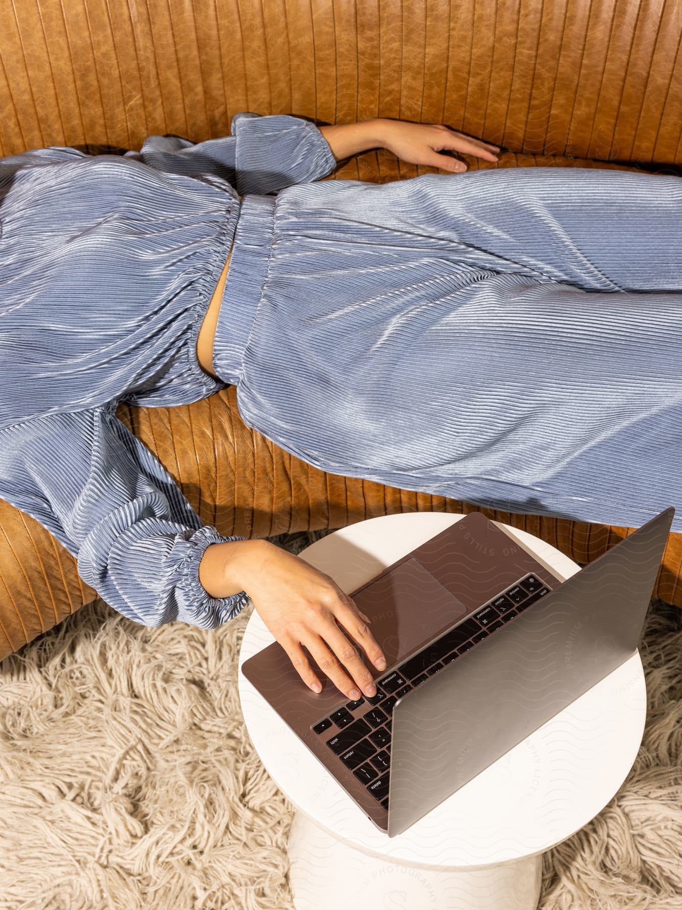 Woman reclined on a vintage couch uses a laptop