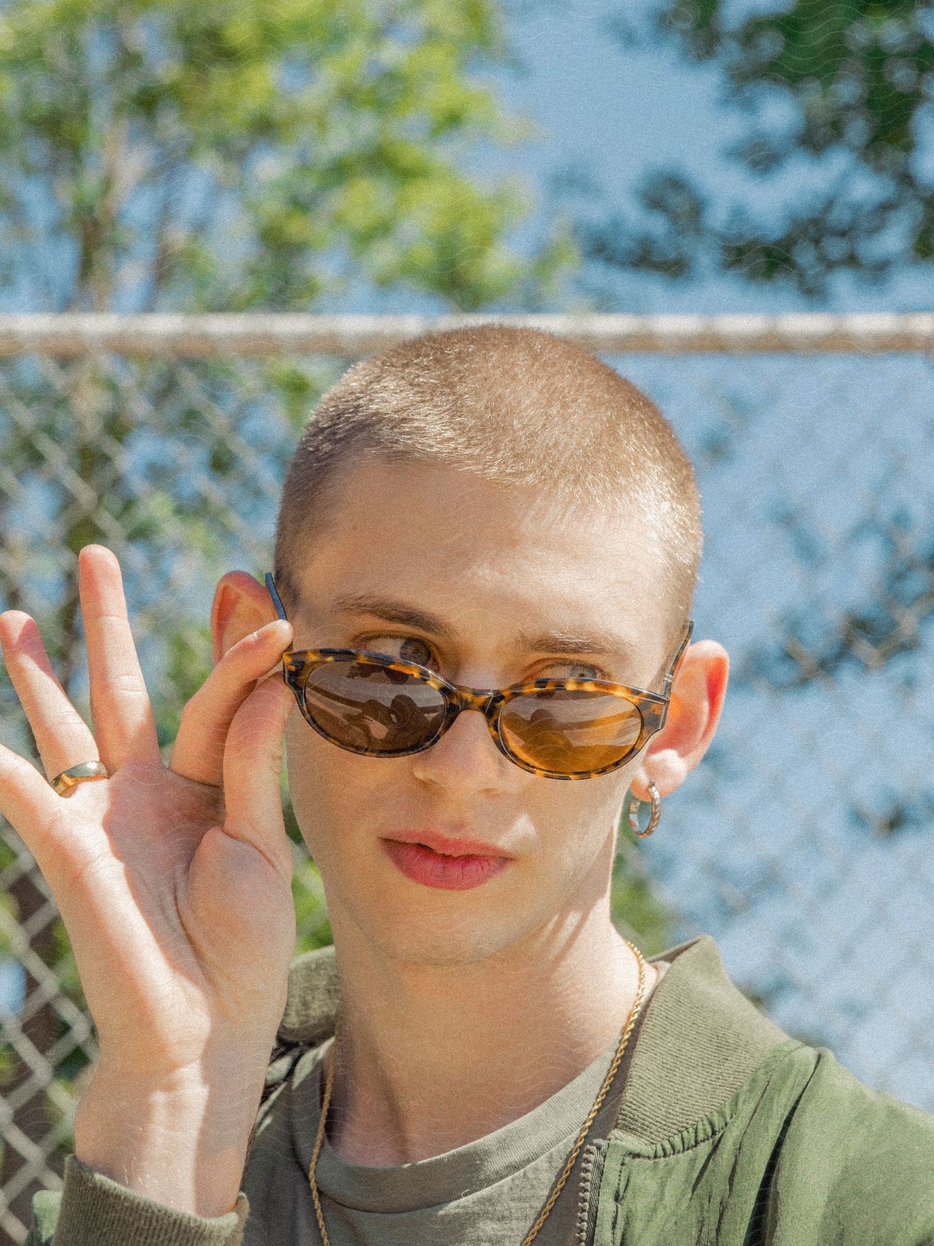 A woman standing outdoors posing with sunglasses.