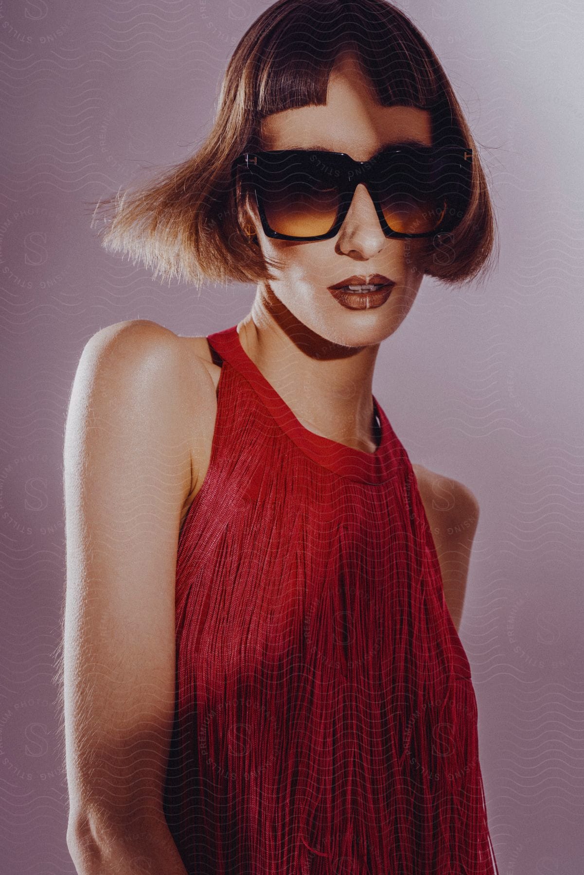 Female model with a bob haircut sunglasses and red TIERED FRINGE MINI DRESS poses for the camera