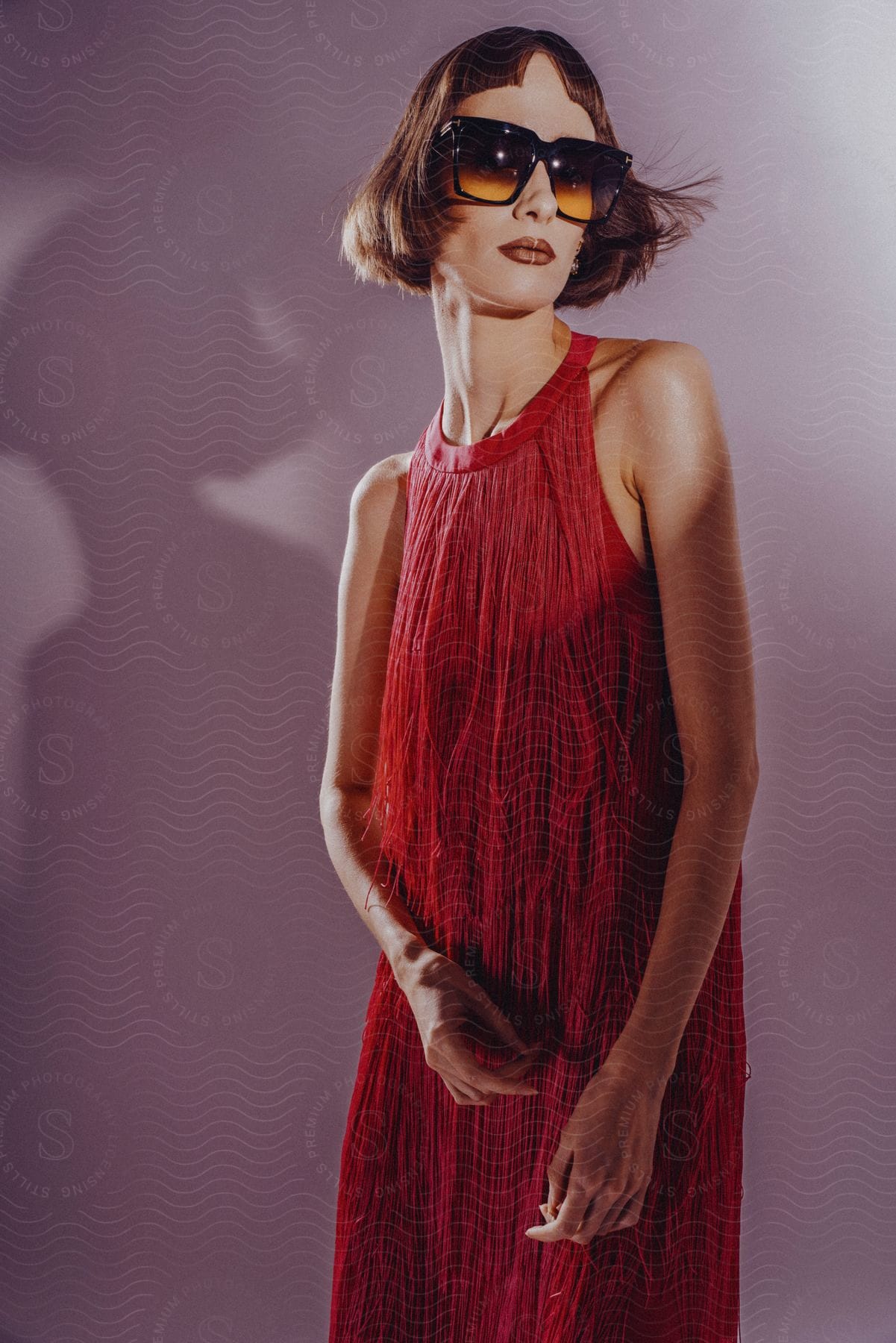 A woman is wearing sunglasses and modeling a red sundress