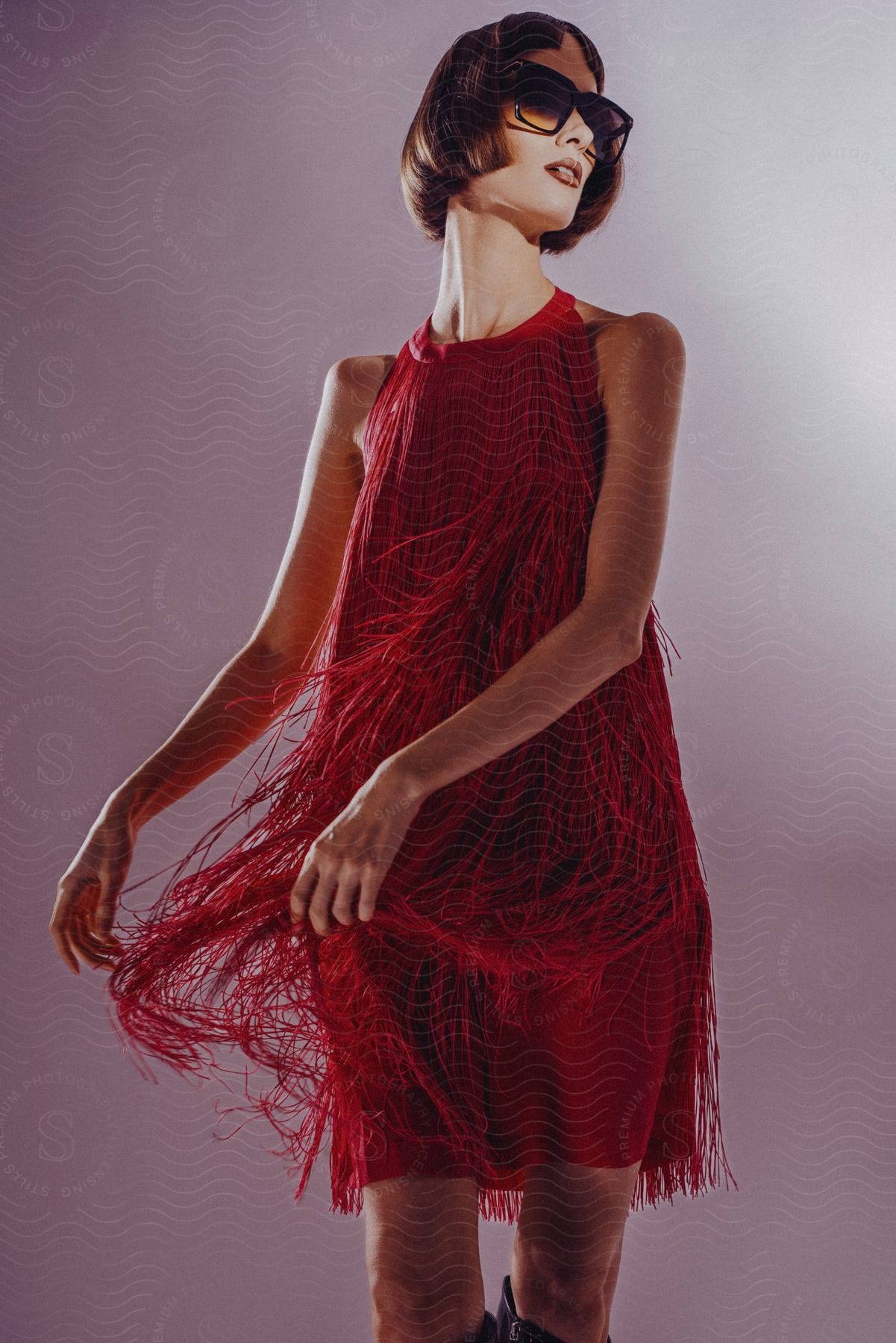 Woman wearing sunglasses and red tiered fringe mini dress poses for the camera