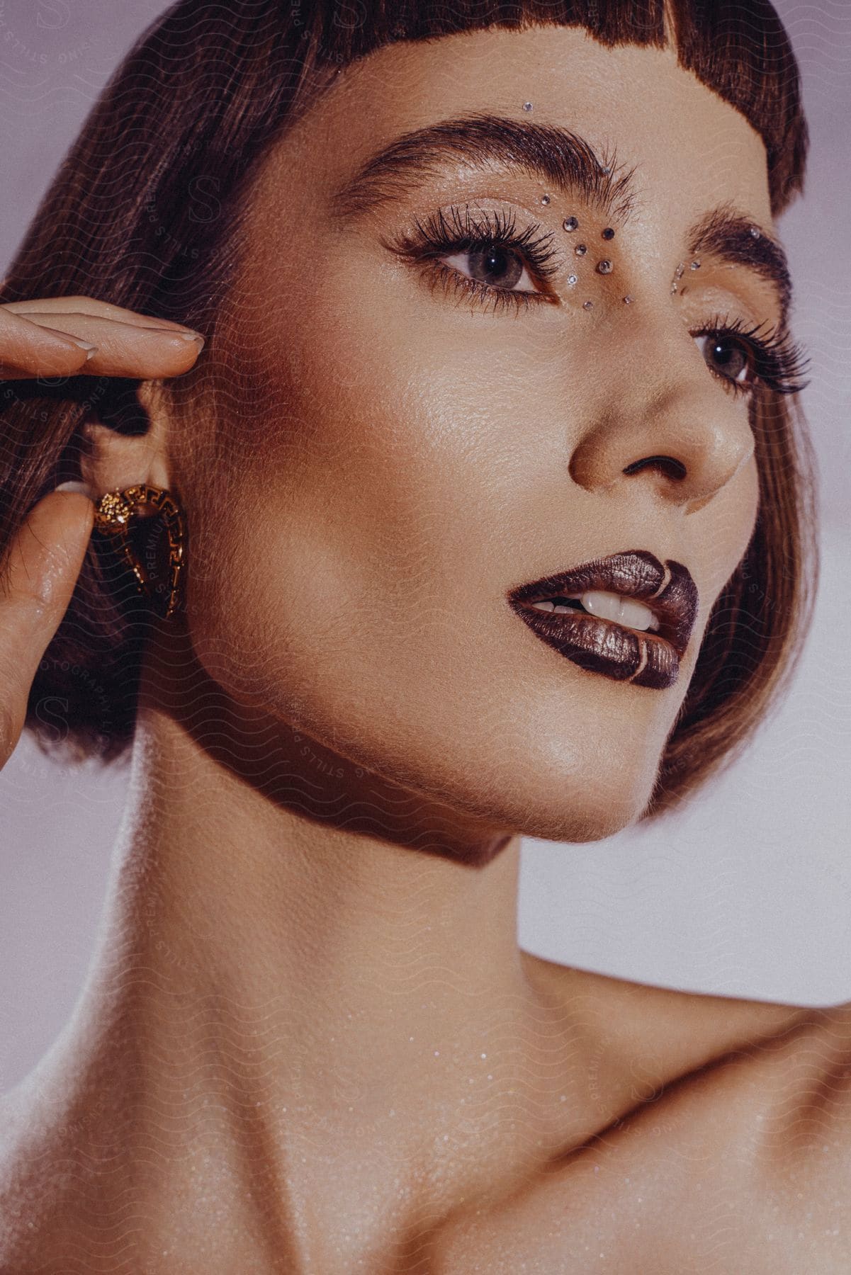 female model with a bob haircut, earrings, and dark lipstick showcases a stylish and captivating look.