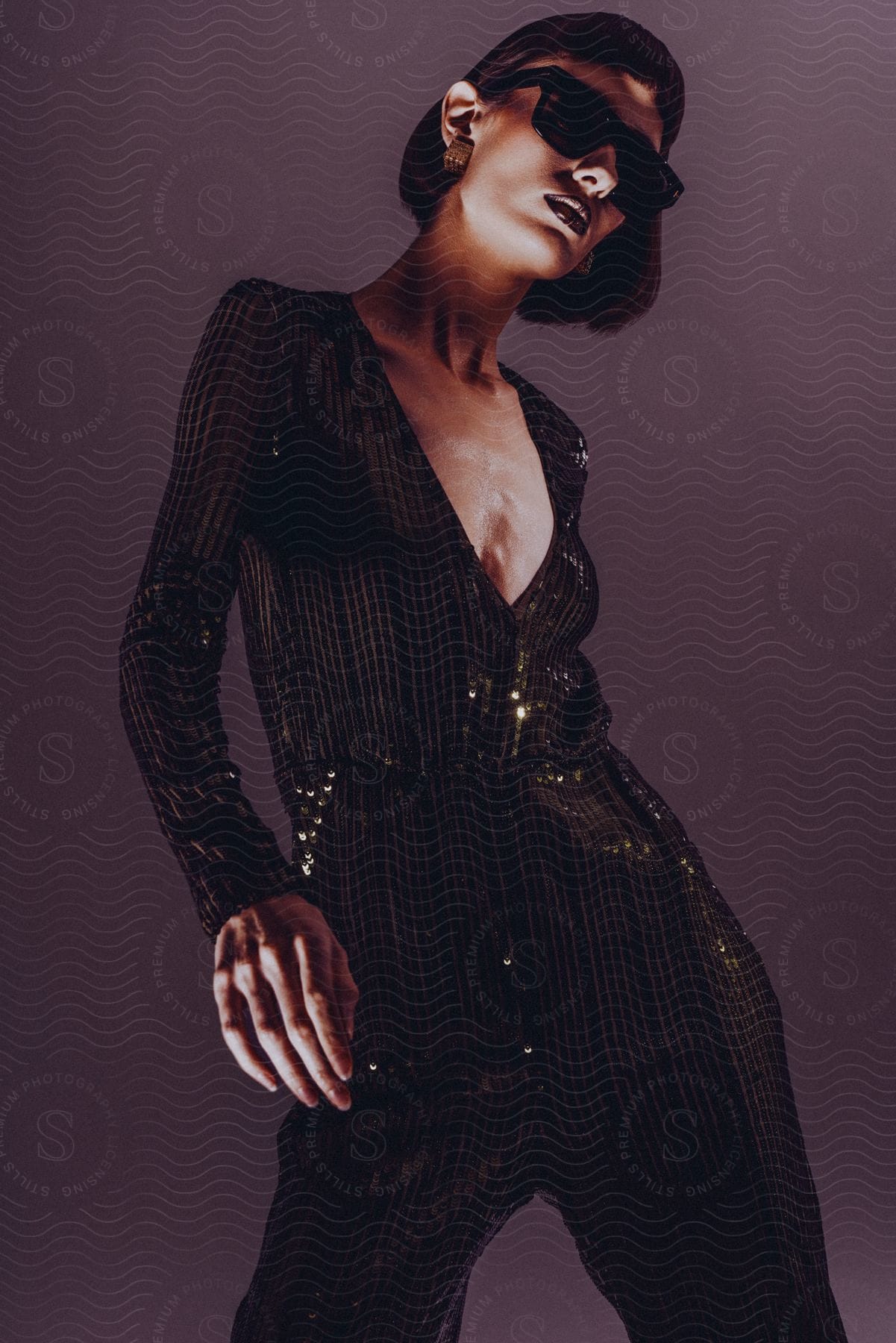 Woman modeling in a long black and shiny dress and wearing sunglasses.