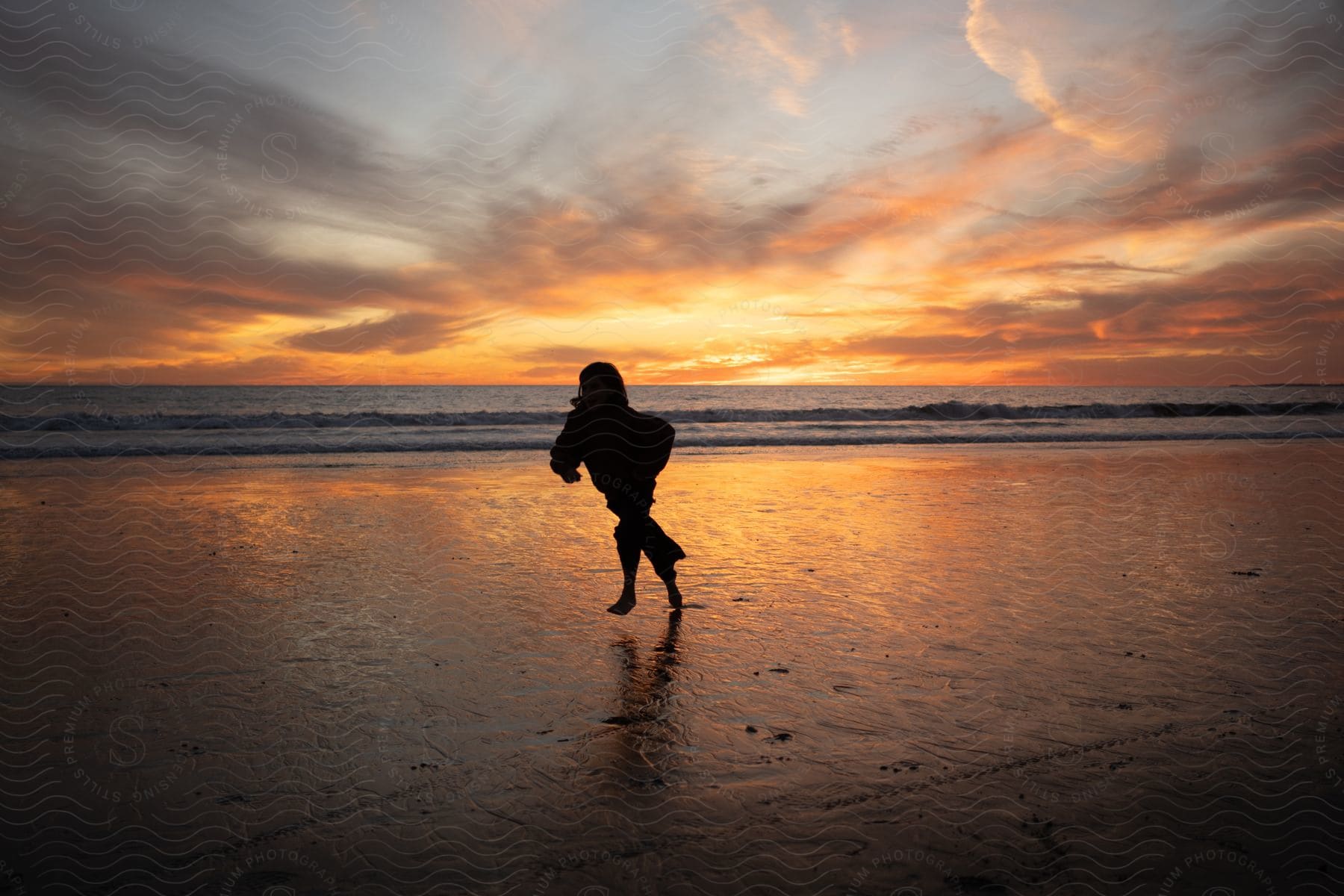 A child running across a beach at sunset.